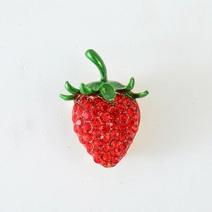 Exquisite strawberry brooch with red crystals and green enamel leaf on a white background