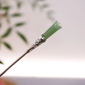 Makroaufnahme einer tulpenförmigen Jade-Haarnadel mit silbernem Durchbruchmuster