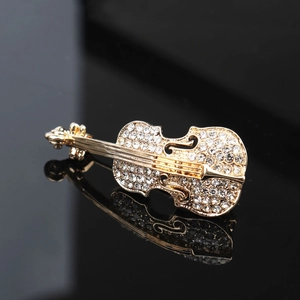Broche violon dorée élégante ornée de strass brillants sur un support en miroir noir chic