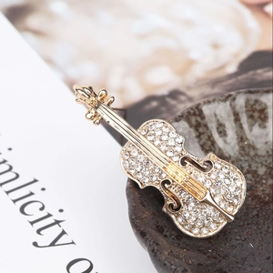 Détail macro d'une broche violon dorée ornée de strass blancs brillants et élégants