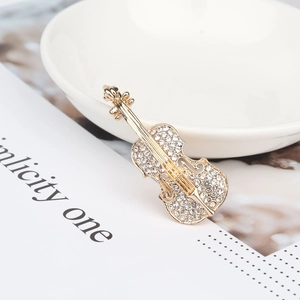 Détail d'une broche violon ornée de strass blancs sur un alliage doré poli
