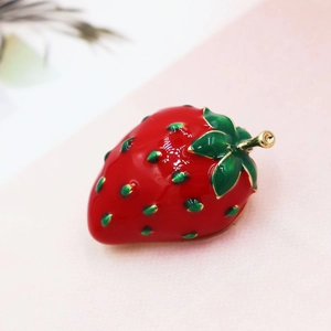 Détail macro d'une broche fraise rouge vif avec feuilles vertes et bordure dorée