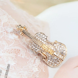 Détail de la broche violon dorée sertie de strass brillants sur un fond de style rétro
