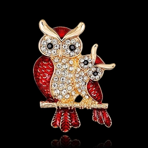 Détails de la broche hibou en émail rouge et strass dorés sur un fond noir élégant