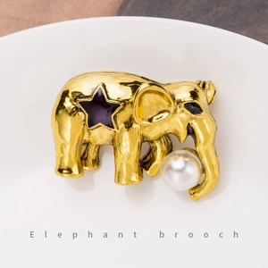 Eleganter goldener Elefanten-Anstecker mit lila Stern und Perle auf weißer Keramik