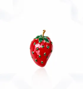 Close-up of vibrant red strawberry brooch with green leaves and gold stem detail