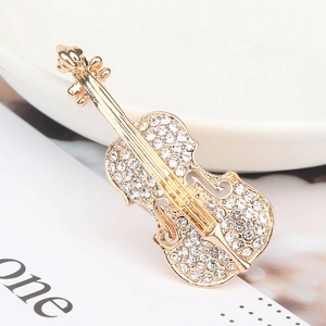 Broche violon dorée tendance avec strass scintillants sur un plateau blanc