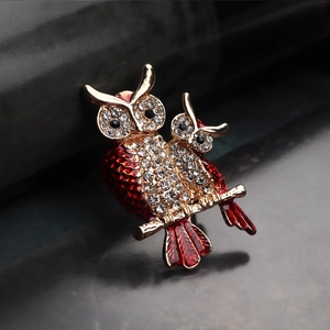 Paire de broches chouettes rouges avec strass et branche dorée sur cuir noir