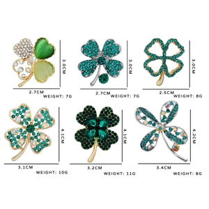 Golden and silver four-leaf clover brooches set with crystal and green glass accents