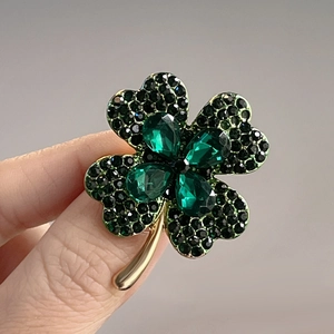 Macro shot of green clover brooch with black crystal pavé and gold finish accents
