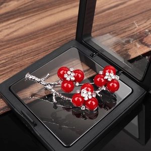 Détail d'une broche fleur de prunier rouge avec branches argentées et cristaux brillants