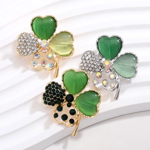 Elegant four-leaf clover brooches with cat-eye stones and rhinestones on white display