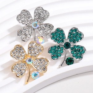 Detailed macro view of sparkling four-leaf clover brooches in gold and silver finishes