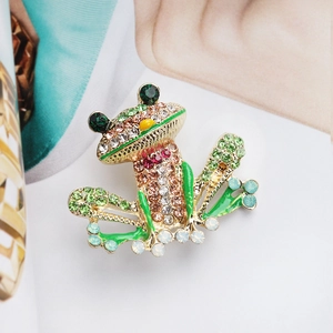 Detalle macro de broche de rana con diamantes de imitación multicolores y aleación dorada
