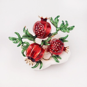 Fashionable retro pomegranate brooch with red enamel seeds and green leaves on white stone