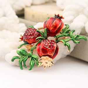 Vintage pomegranate brooch featuring red enamel fruit and green leaves in gold-tone setting