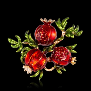 Vintage pomegranate fruit brooch with red enamel seeds and green leaves on golden branch