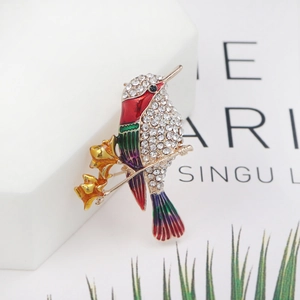 Macro shot of hummingbird brooch with colorful enamel wings and crystal pavé on branch