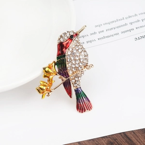 Detailed close-up of bird brooch with colorful enamel flowers on a golden branch