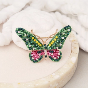 Spilla a farfalla vintage con smalto verde e strass su un vassoio decorativo