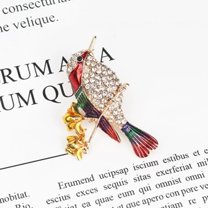 Macro shot of hummingbird brooch with colorful enamel wings and crystal rhinestones