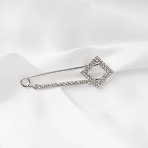 Macro de un broche de aleación plateada con diamantes de imitación sobre seda blanca