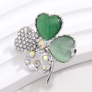 Macro shot of clover brooch featuring green cat-eye stones and glittering rhinestones