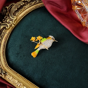 Exquisite hummingbird brooch with green enamel feathers and white crystals on a gold base