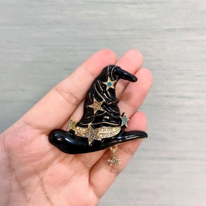 Detail of a black enamel wizard hat brooch with colorful rhinestones and gold star pendant