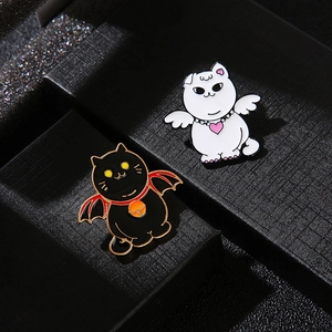 Gros plan de badges en émail chat ange et démon sur une boîte à bijoux noire
