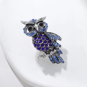 Elegant silver owl brooch with sparkling blue and black crystals on a branch