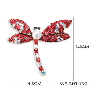 Detail showing vintage dragonfly brooch with red and white crystals and center pearl