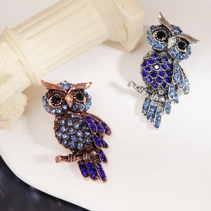Macro shot of owl brooches with gradient blue rhinestones on copper and silver bases
