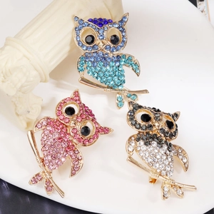 Gros plan détaillé de trois broches chouettes étincelantes en strass sur une assiette