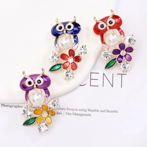 Détail de broches hibou en émail avec perles et cristaux en tons violet, bleu et rouge