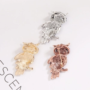 Detailed back view of owl brooches showing safety pin clasp and textured alloy finish