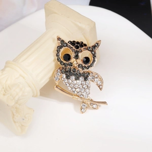Gros plan d'une luxueuse broche hibou en strass posée sur une colonne romaine blanche