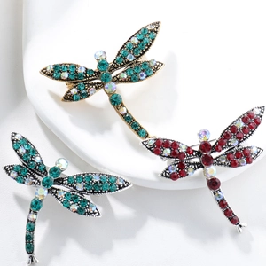 Detailed close-up of dragonfly brooches with sparkling rhinestones on ceramic display