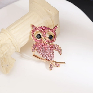 Gros plan détaillé d'une broche hibou en strass roses sur une branche d'or rose vintage