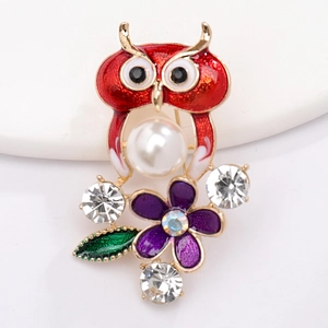 Détail de la broche hibou avec émail rouge, perle blanche et strass brillants
