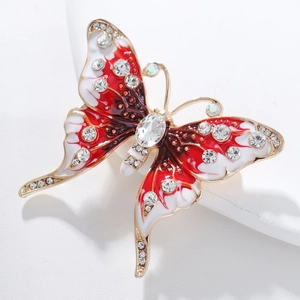 Dettaglio macro di spilla a farfalla vintage con smalto rosso e strass brillanti