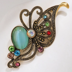 Macro detail of vintage gold brooch with colorful rhinestones and green cat-eye stone