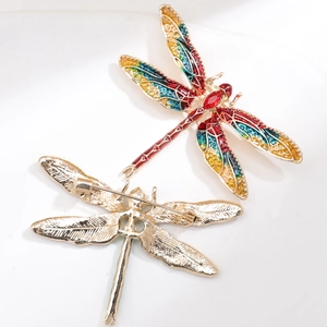Detail view of colorful enamel dragonfly brooch with golden textured metal back