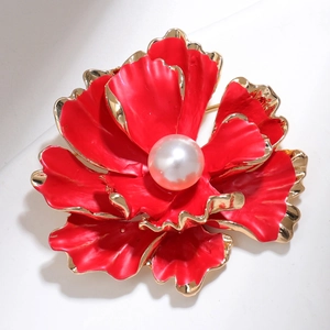Macro view of red flower brooch featuring gold-edged petals and a white pearl center