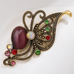 Detailed close-up of vintage gold brooch with purple gemstone and multicolor crystals