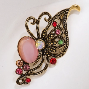 Macro shot of vintage gold brooch with pink opal stone and colorful rhinestones