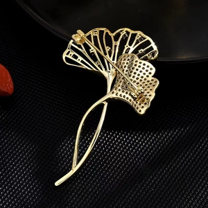 Broche luxueuse en feuilles de ginkgo dorées avec texture évidée sur fond noir