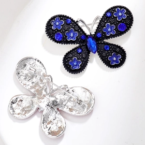 Dettaglio di spille a farfalla con strass blu e chiusura di sicurezza in spilla metallica