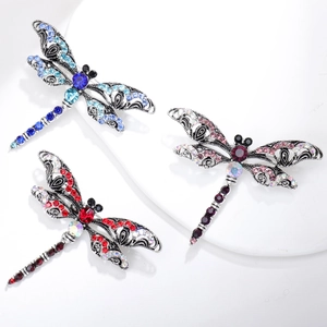 Macro detail of three colorful dragonfly brooches with rhinestones and filigree wings