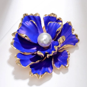 Macro shot of dark purple floral brooch with golden edges and a large central pearl